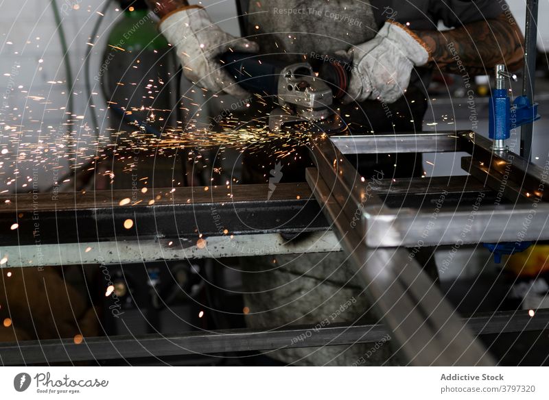 Male worker using electric grinder in workshop machine man cut welder metalwork spark male detail industry instrument skill tool manufacture equipment