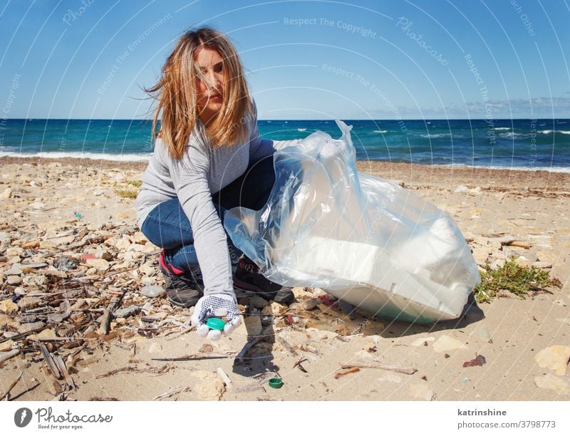 Young woman cleaning beach area and showing plastic bottle lids in hand bag sea Collecting Nature Volunteering Activist Coast Environment Outdoor Picking