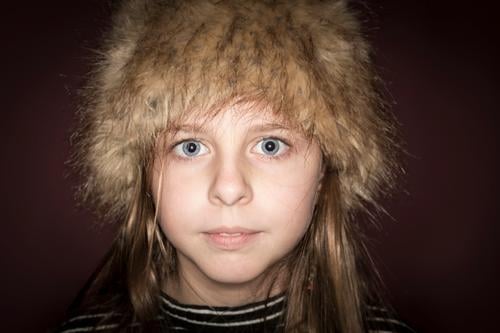 Studio portrait of a cute girl with long blonde hair wearing a winter hat against brown background pretty girl studio portrait european caucasian blue eyes