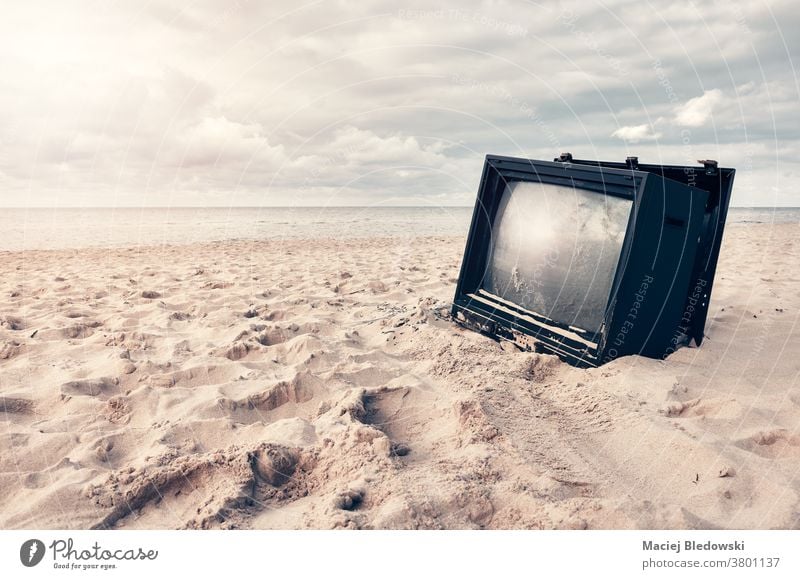 Old broken TV set on a beach at sunset. television sand screen obsolete news nature old technology sky peaceful relax media pollution nobody garbage tv damaged