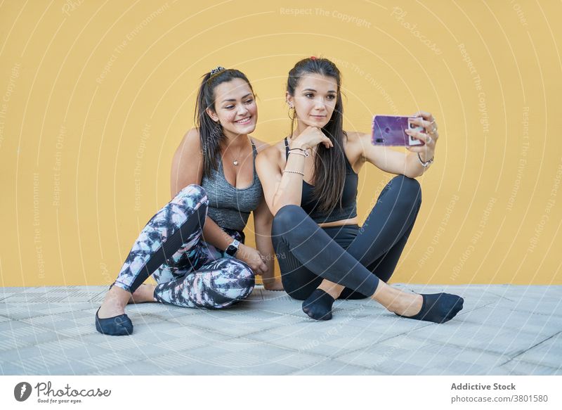 Positive women sitting on floor and taking selfie on smartphone content positive gadget friend cheerful using moment modern young mobile social media browsing