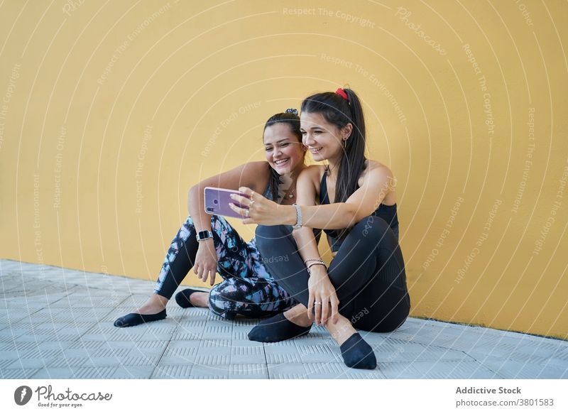 Positive women sitting on floor and taking selfie on smartphone content positive gadget friend cheerful using moment modern young mobile social media browsing