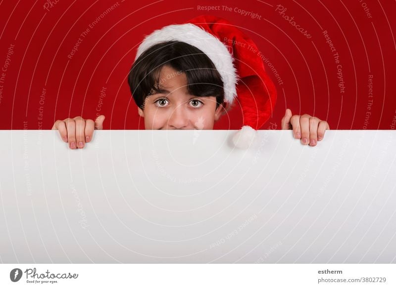 Merry Christmas,smiling kid Wearing Christmas Santa Claus hat holding blank board child christmas santa claus x-mas celebration santa hat advertisement fun