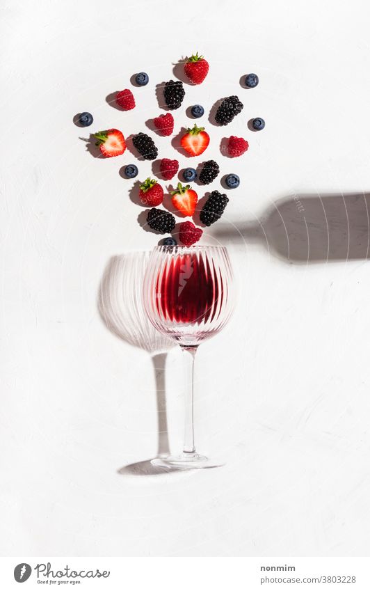 Concept composition presenting red wine flavours of summer fruits of berries concept glass goblet flatlay berry taste shadow alcohol bar beverage blush color