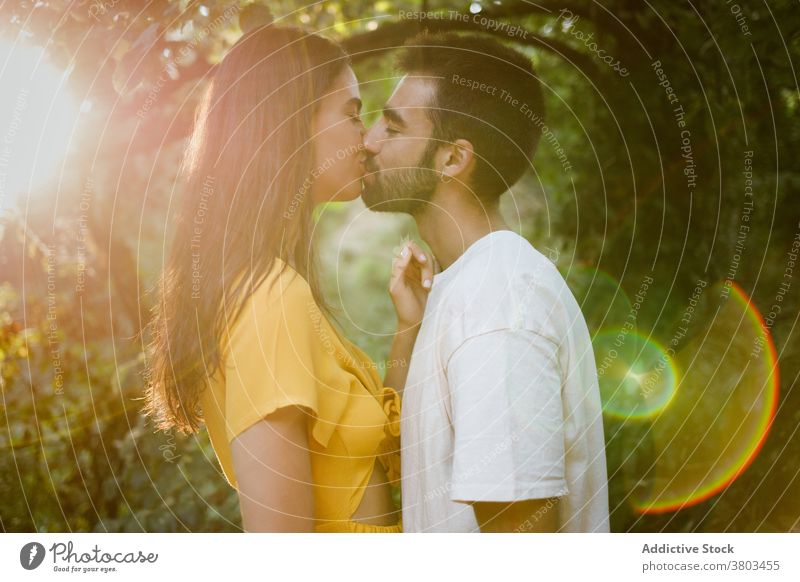 Happy ethnic couple kissing in forest romantic date love together park smile relationship relax positive happy boyfriend girlfriend young casual dark hair