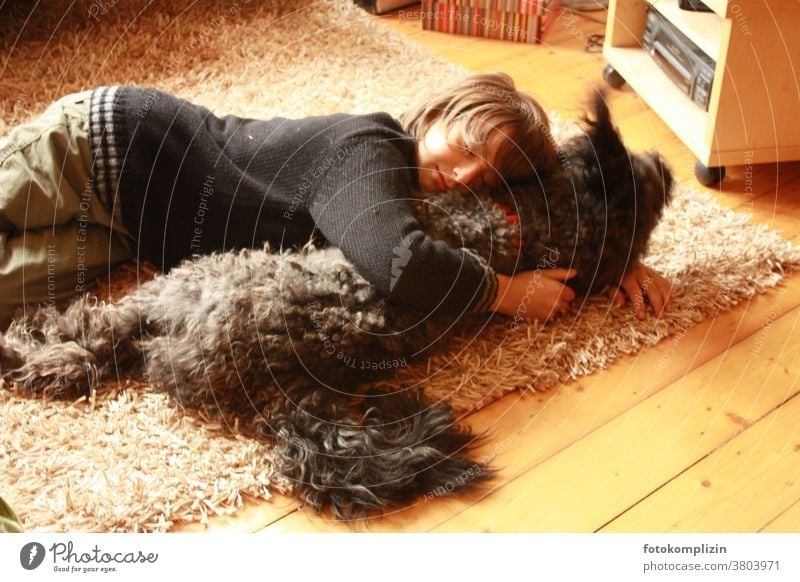 Boy lies on a carpet with a dog Pet tenderness Cuddling Infancy proximity tie Friendship dog love Humans and animals experience together in common Common ground