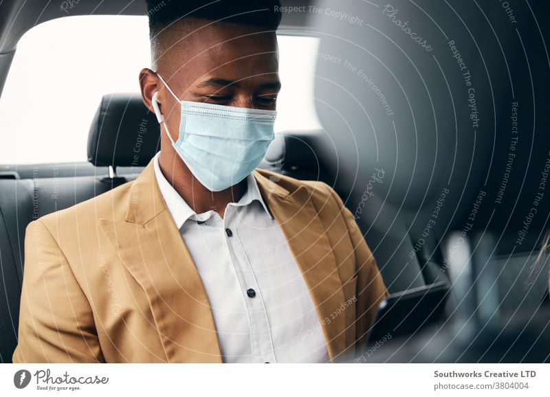Young Businessman Wearing Mask Checking Mobile Phone In Back Of Taxi During Health Pandemic business businessman taxi face mask face covering wearing ppe cab