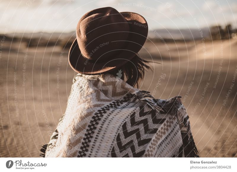 young woman from backwards with scarf and hat in the desert at sunset - a  Royalty Free Stock Photo from Photocase