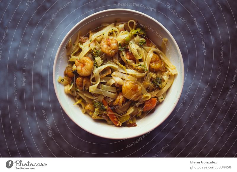 bowl of noodles with vegetables and shrimp on dark background. Asian food concept. Top view chinese onion pasta dishes pepper spicy carrots isolated spices