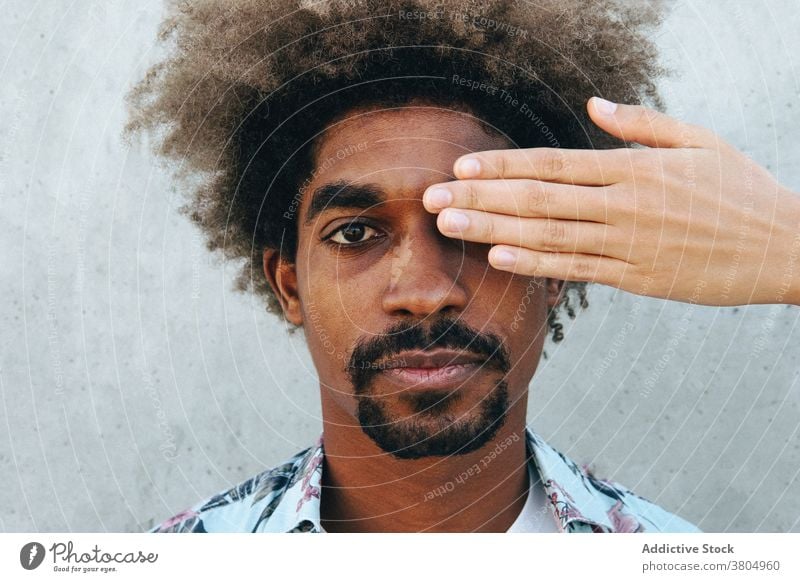 Crop partner covering eye of black man near cement wall cover eye friend focus stylish appearance afro hairstyle attentive portrait trendy modern casual