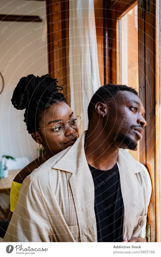 Positive black wife looking at thoughtful husband in cozy room couple toothy smile positive pensive interior contemplate together happy relationship