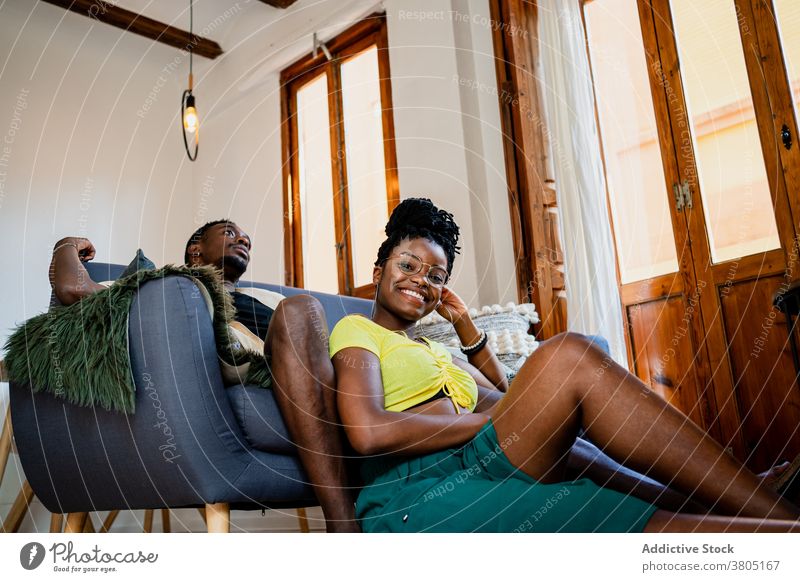 Black couple relaxing in living room cheerful rest sofa cozy interior free time weekend chill african american black carpet table frame wooden couch optimist