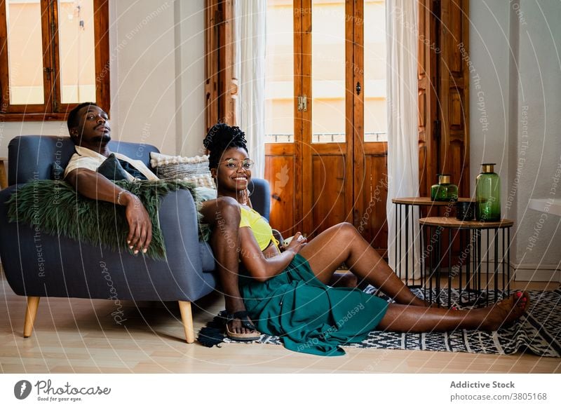 Black couple relaxing in living room cheerful rest sofa cozy interior free time weekend chill african american black carpet table frame wooden couch optimist
