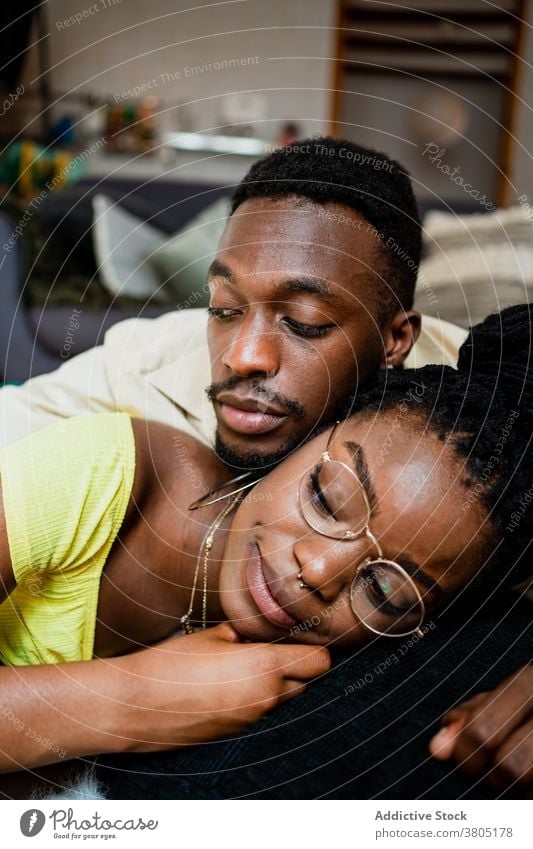 Cheerful young African American couple cuddling while lying on floor at home cuddle spend time together happy love romantic relax weekend relationship affection