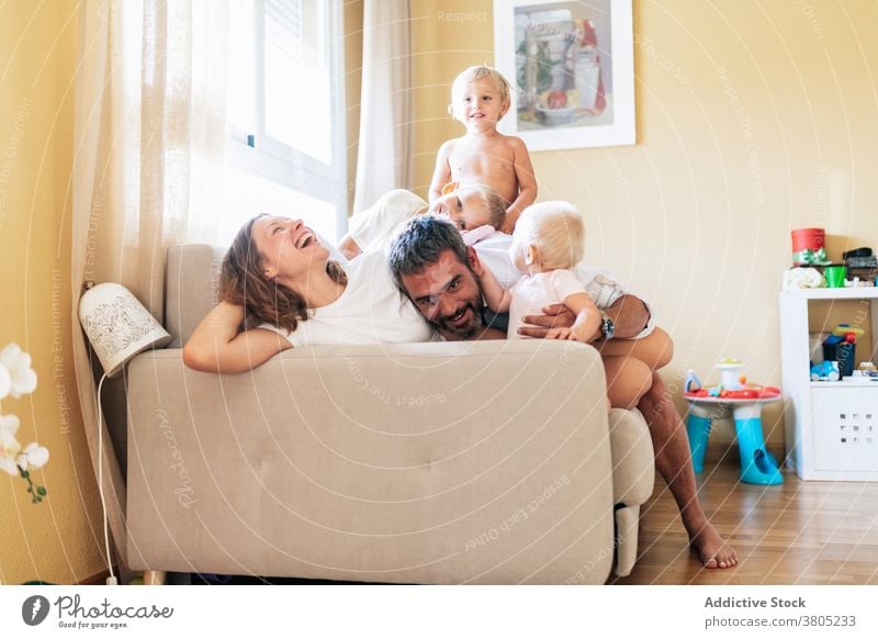 Happy family having fun on couch play sofa spend time together playful mother father children home relationship adorable love adult baby preschooler apartment