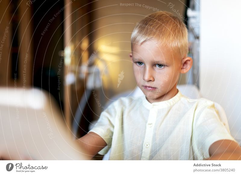 Focused boy watching films on tablet browsing kid child smart leisure serious concentrate online blond internet gadget device surfing connection modern focus