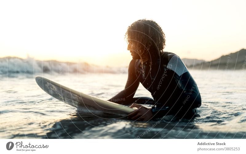Concentrated surfer looking at coming wave man sea ocean water sports summer focus leisure surfboard male serious pensive curly hair wetsuit vacation beach