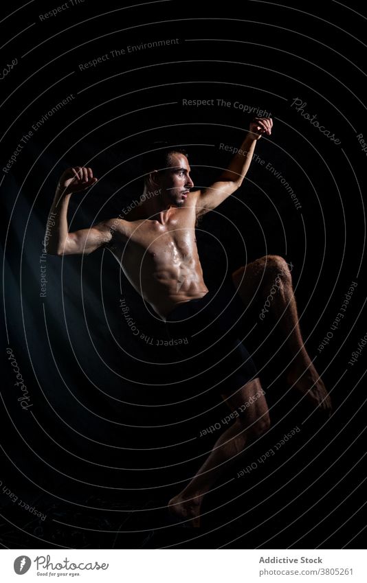 Sporty dancer training in dark room man arm raised motion perform rehearsal energy expressive muscular neon male shirtless sporty practice flexible slim