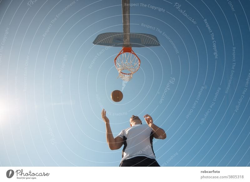 man playing basketball an outdoor court on the street. fun sport urban people cool men shot young game male adult jump hoop score competition leisure african