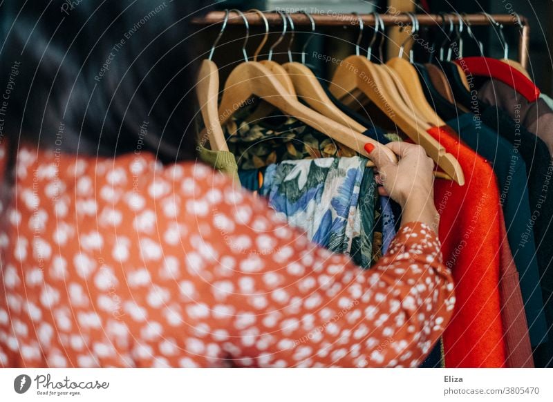 A woman rummages for clothes at a clothes stall in a second hand shop or flea market garments Flea market clothes rail vintage Sustainability Fashion Clothes