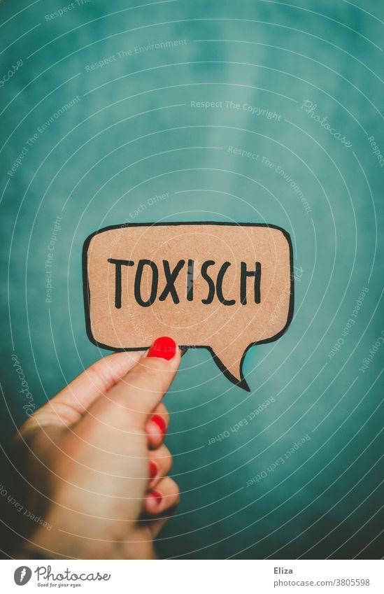 A female hand holds a speech bubble containing the word toxic in front of a turquoise background. Toxic Speech bubble communication relation Emotions Unhealthy