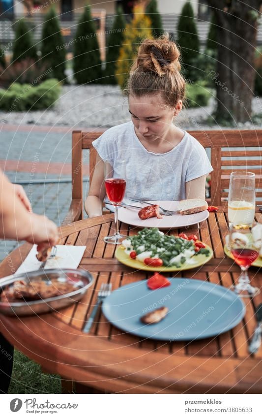 Family having a meal during summer picnic outdoor dinner in a home garden feast food man together woman child barbecue table eating gathering people lifestyle