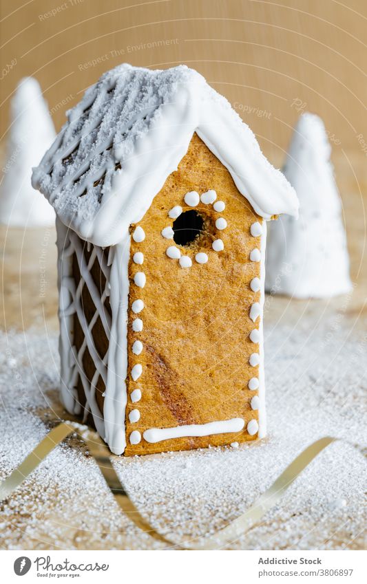 Tasty gingerbread house decorated with icing sugar glaze pastry baked treat festive ornament delicious holiday bright powdered decorative roof hole colorful