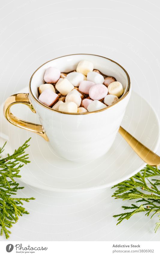 Cup of hot chocolate with marshmallows on white background cup hot drink sweet delicious treat confectionery creative design decor ceramic saucer golden