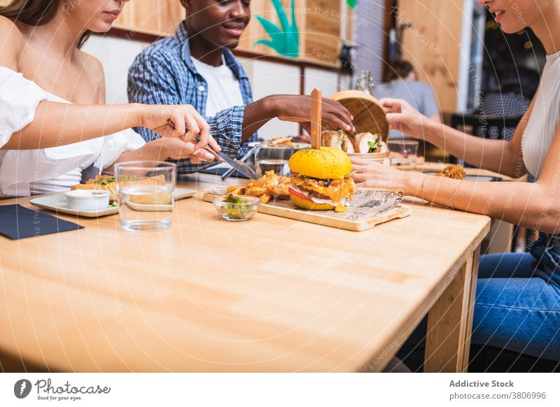 Content multiethnic friends having dinner in cafeteria eat dine together restaurant positive tasty food friendly meet delicious cheerful gather hungry young