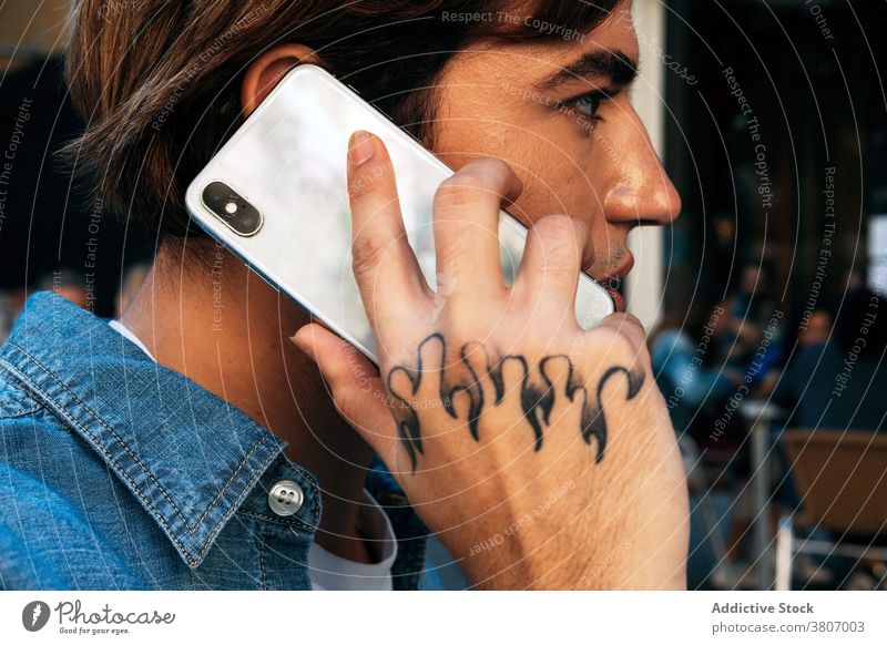 Young man with tattoo talking on phone smartphone call mobile hipster communicate modern young male conversation device gadget connection speak lifestyle