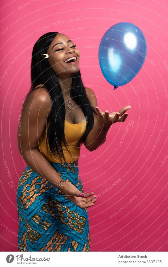 Cheerful young African American female playing with balloon in studio woman happy cheerful joy style model smile fashion playful positive optimist ethnic black