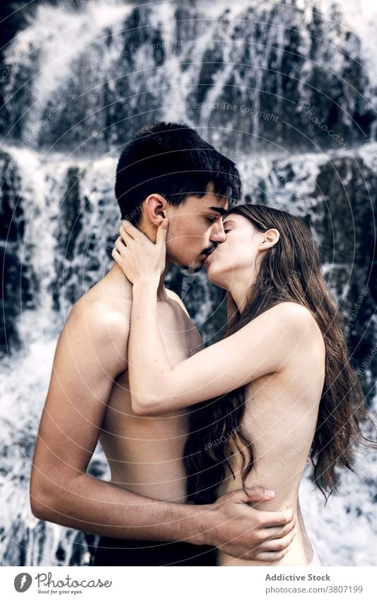 Tender naked couple embracing near waterfall tender hug nature love kiss kissing nude carefree embrace summer affection romantic together enjoy relationship