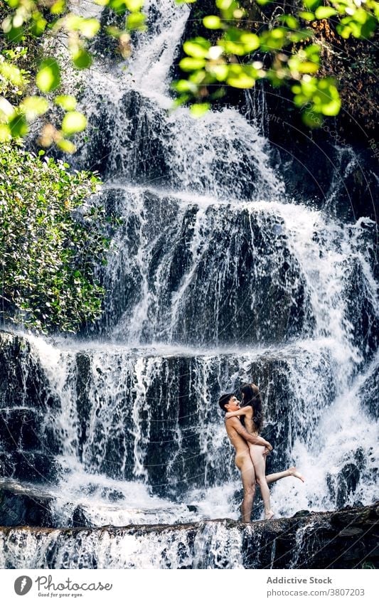 Naked couple hugging near waterfall naked nude vacation together erotic embrace tender summer romantic love relationship intimate nature girlfriend harmony