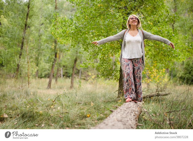 Happy woman standing on tree trunk in forest balance summer freedom travel nature green explore verdant greenery foliage female adventure vacation enjoy happy