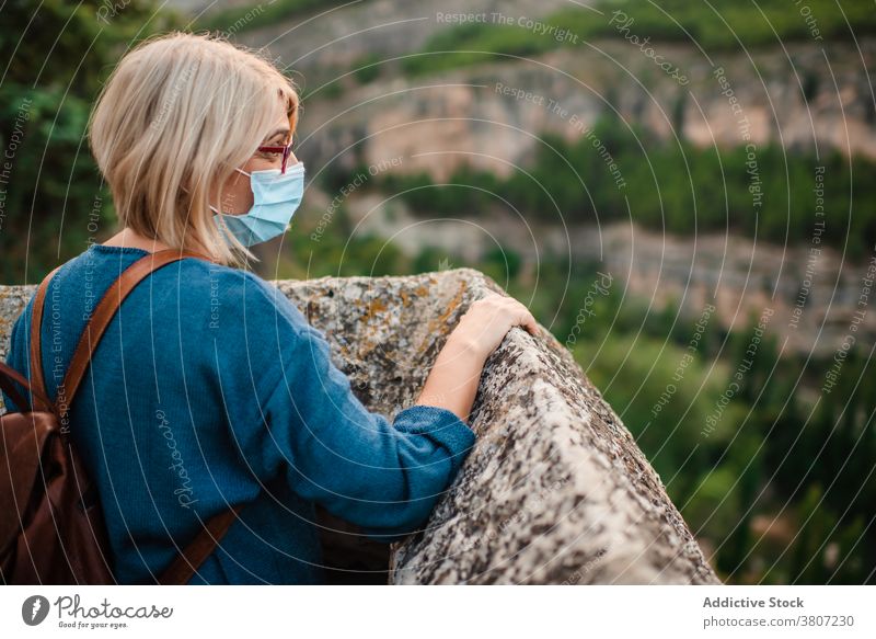 Woman in mask observing mountains from ancient castle woman traveler historic medieval explore rock fortress coronavirus old cuenca spain journey female observe