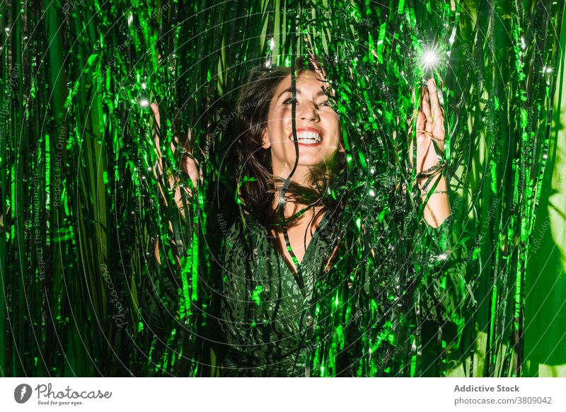 Cheerful woman playing with green tinsel party stripe having fun playful foil color vibrant female shiny dress festive happy cheerful delight enjoy trendy