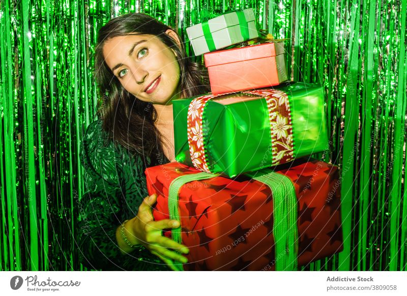 Smiling woman with pile of gifts at Christmas party christmas present tinsel green color box foil shiny female glamour glad stack dress festive charming