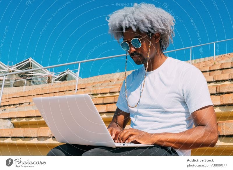 Afro and black man with sunglasses working with his laptop on th working with laptop afro afro man businessman black businessman working outdoors typing