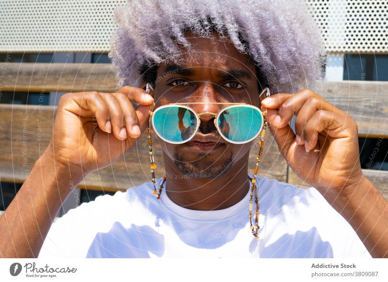 Black man with afro hair putting on sunglasses. Sunglasses and a black man african afro man style model black model gray hair summer putting on glasses