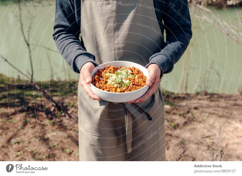 Crop cook with bowl of tasty minced meat in countryside rural man dish prepare delicious apron male garden cuisine chef green onion meal food culinary gourmet