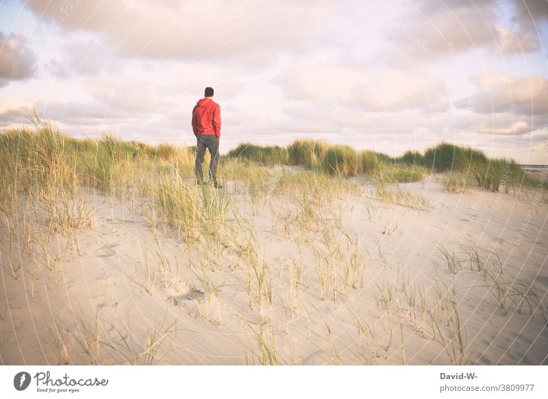 A man stands alone in the dunes and enjoys the silence Man Holidaymakers silent tranquillity gap vacation Stand Ocean Beach Nature Vacation & Travel