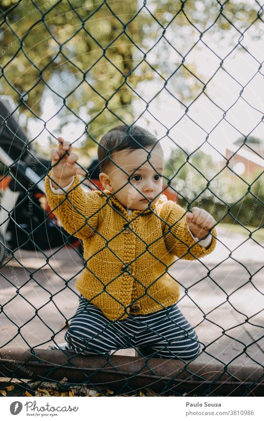 Child holding on a fence Fence Barrier Barred security Safety Kindergarten Border Protection Wire Wire netting childhood Freedom Caucasian Toddler colorful