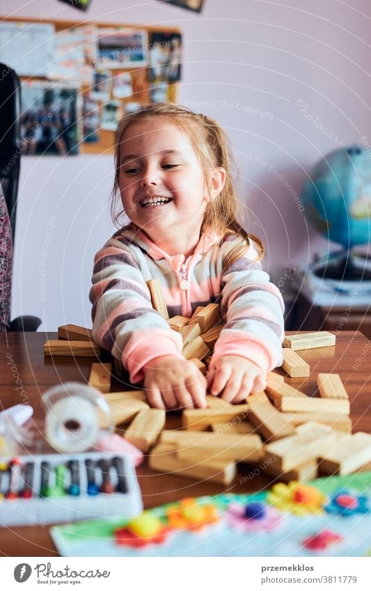 Little girl preschooler playing with wooden blocks toy building a house activity brick child childhood concept construction creativity education fun funny game