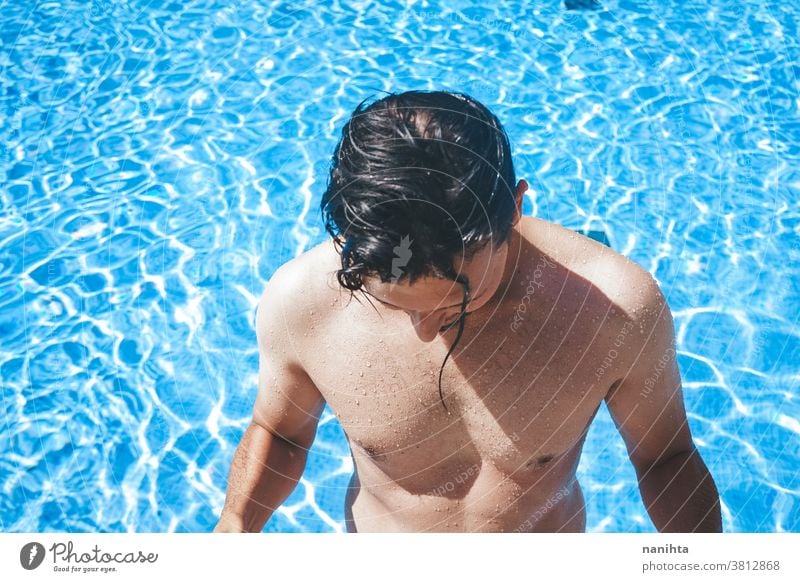 Young handsome man posing near a pool attractive sexy male swimming pool summer skin beard guy smile tan blue water party portrait portraiture real people cool
