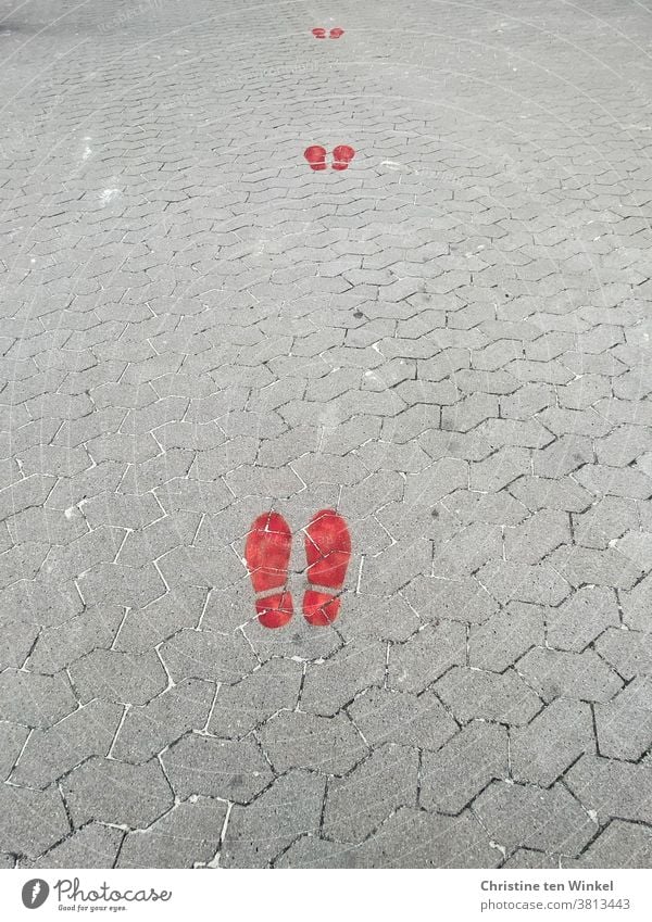 Keep your distance...  red footprints on gray cobblestones | corona thoughts gap minimum distance coronavirus keep sb./sth. apart Warning colour pandemic