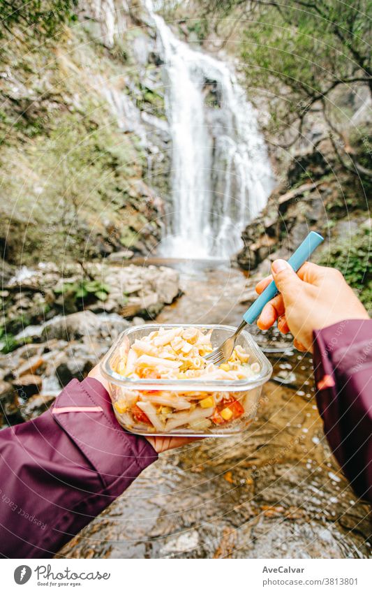 Point of view shot of a female hiker eating in front of a waterfall cook survival picnic ravenous people backpacking relaxation group camp tent bottle forest