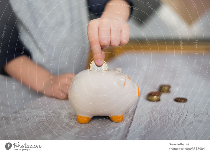 Child putting a coin into piggy bank at home banking budget cash caucasian ceramics child childhood coins concept crisis debt deposit earn economize economy
