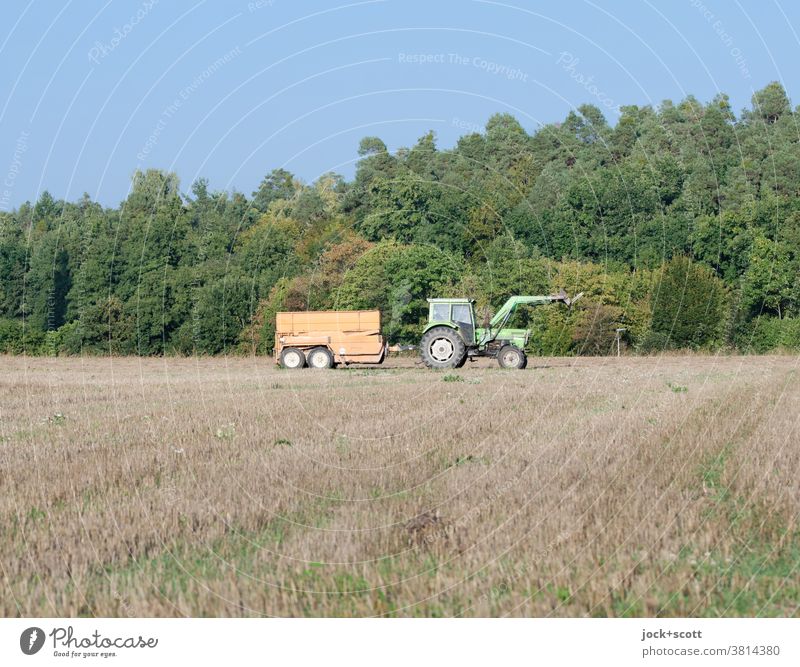 Trailer behind pulling tractor drives over the field Tractor Nature Agriculture Forest Work and employment Environment Landscape Driving Field Cloudless sky