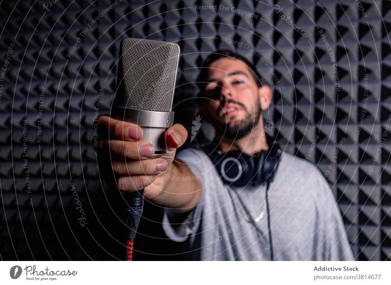 Male musician with microphone in studio sound proof record man singer male artist acoustic room foam song device equipment professional audio modern melody