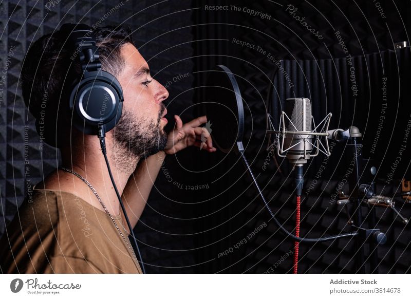 Man in recording studio microphone sing man artist singer headphones acoustic foam male sound proof song room music musician modern contemporary gadget listen